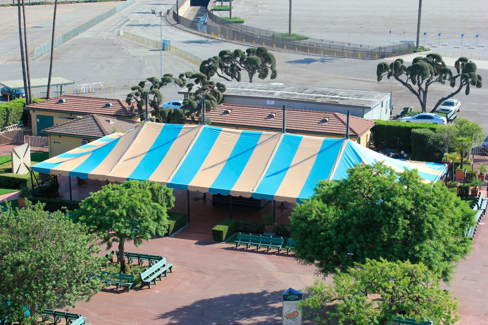Aerial view of a run of large peaked structures with striped tops covering a paved site.
