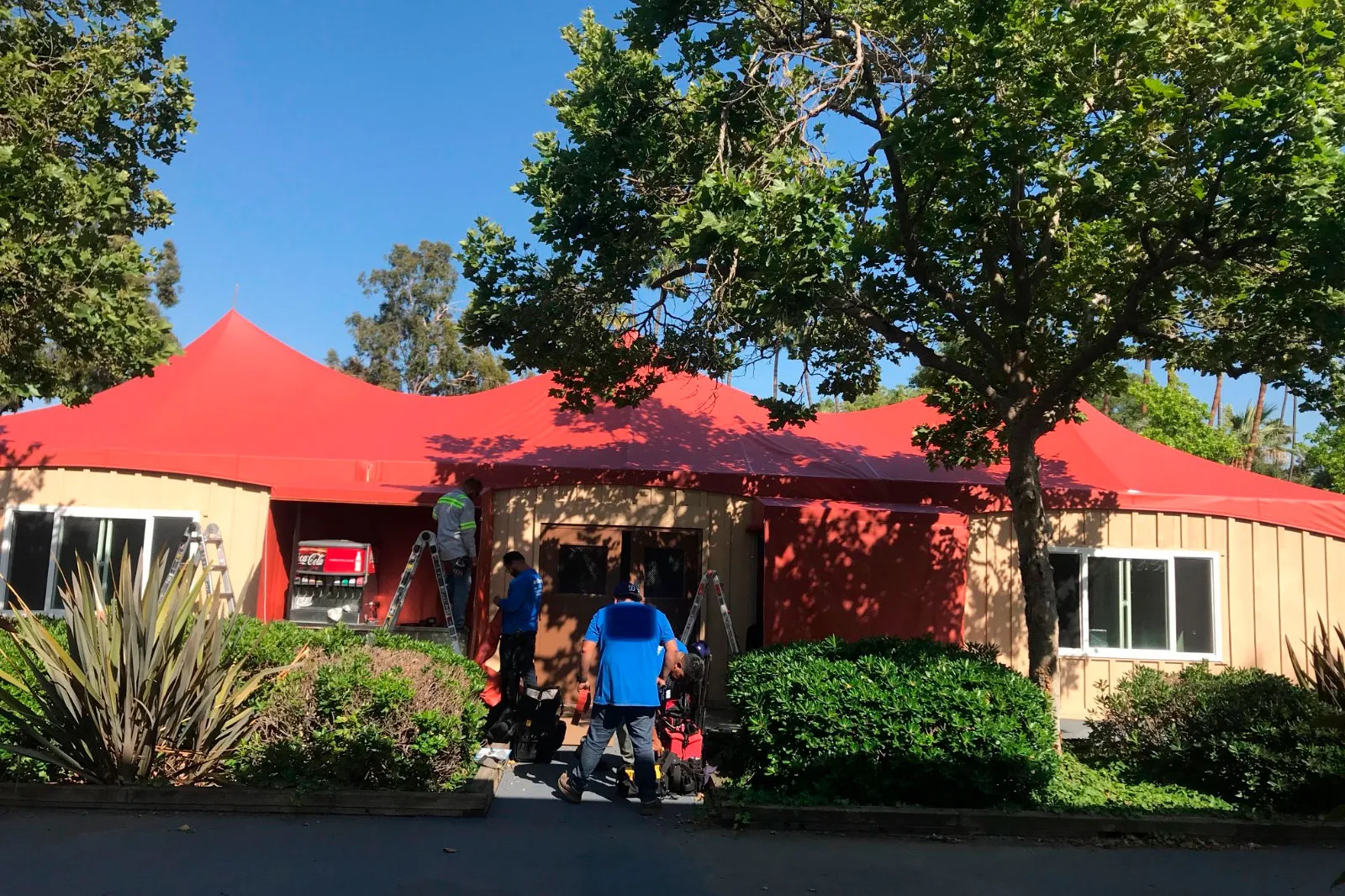 A run of red-topped canopies fronting a building, with people walking beneath.