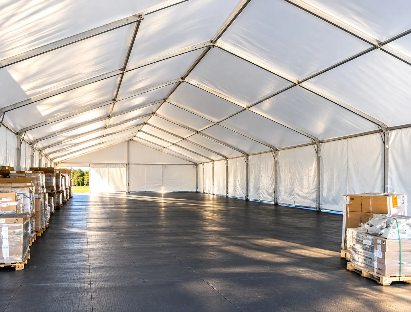The interior of a large clearspan structure, showing the arched aluminum beam frame running the full length with no centre poles.