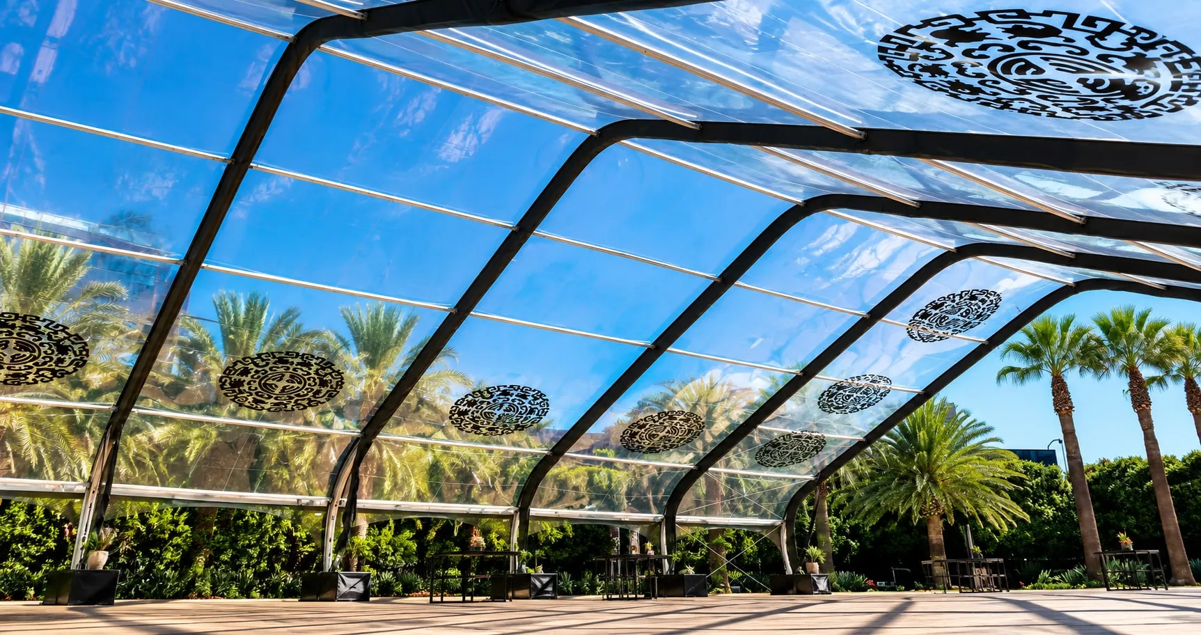 The frame of a large structure seen from inside before the fabric is fitted, with daylight through the open end.