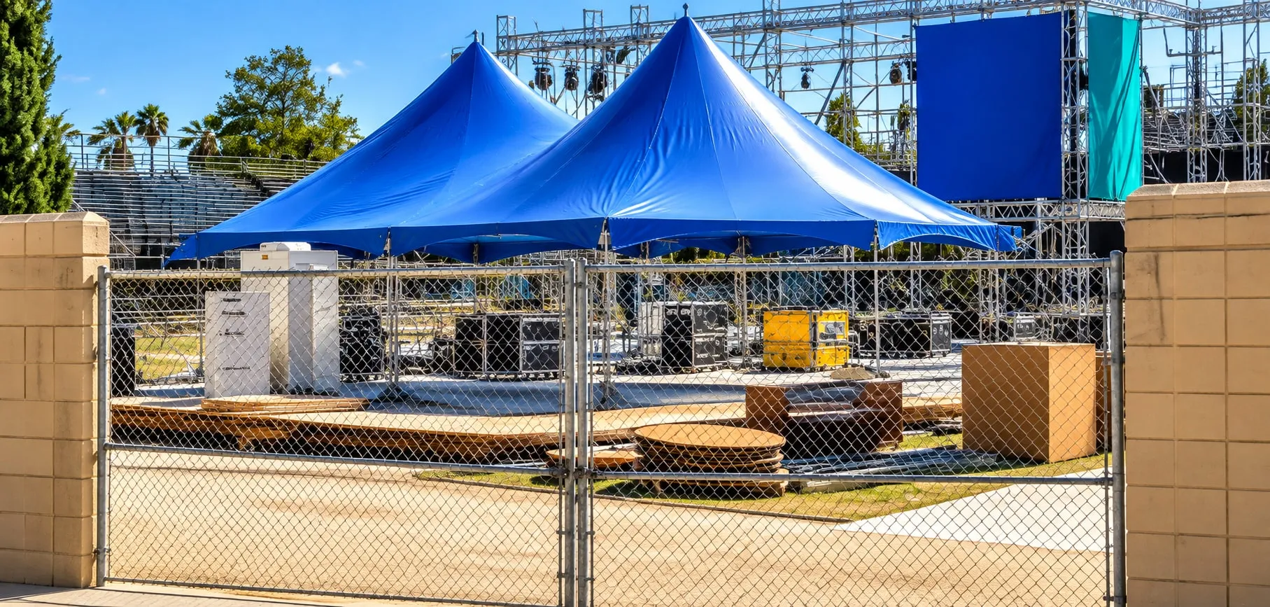 Two blue high peak tents set up beside a stage build on an event site.