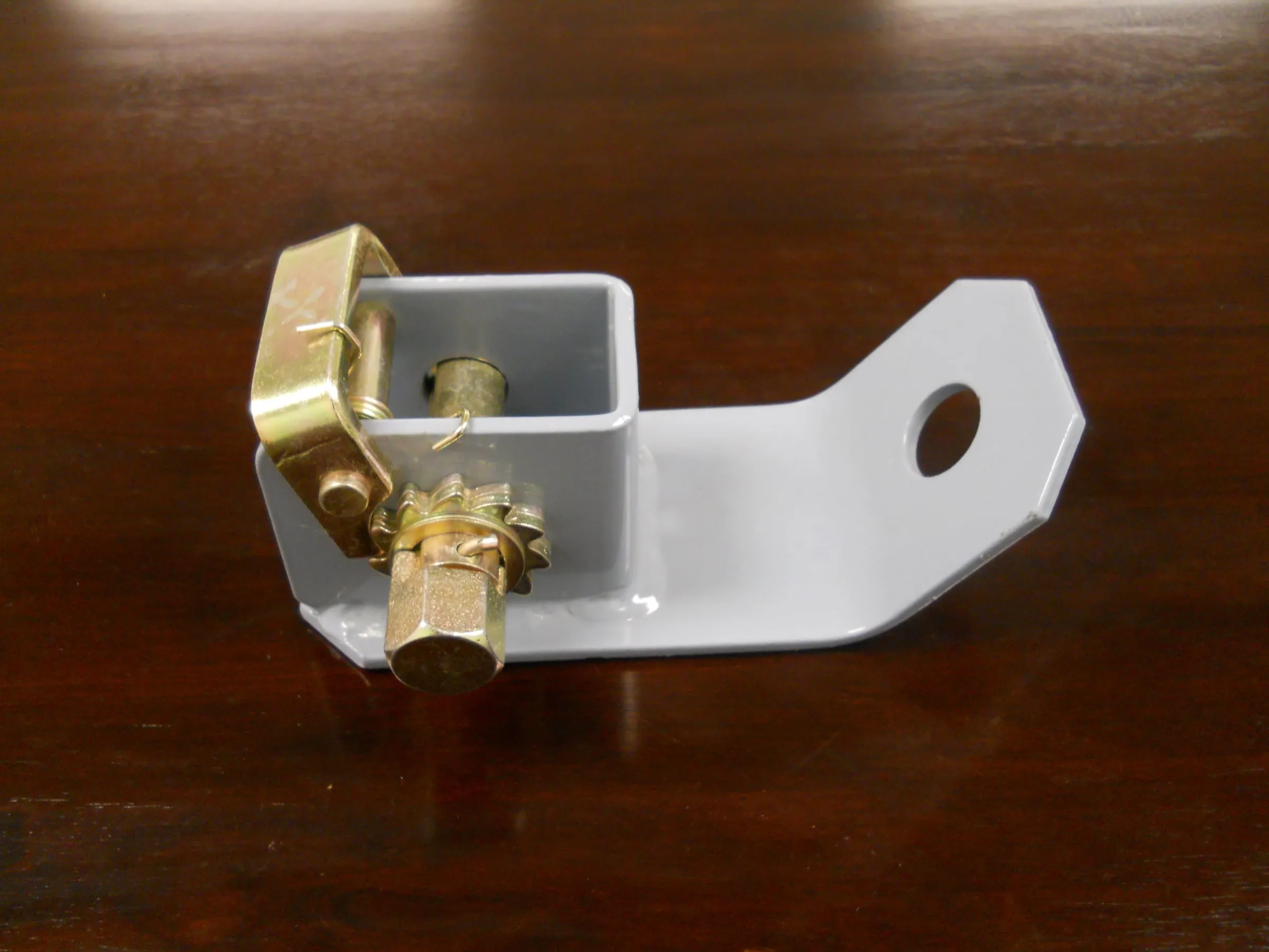 A zinc-plated ratchet mounted on a steel bracket.