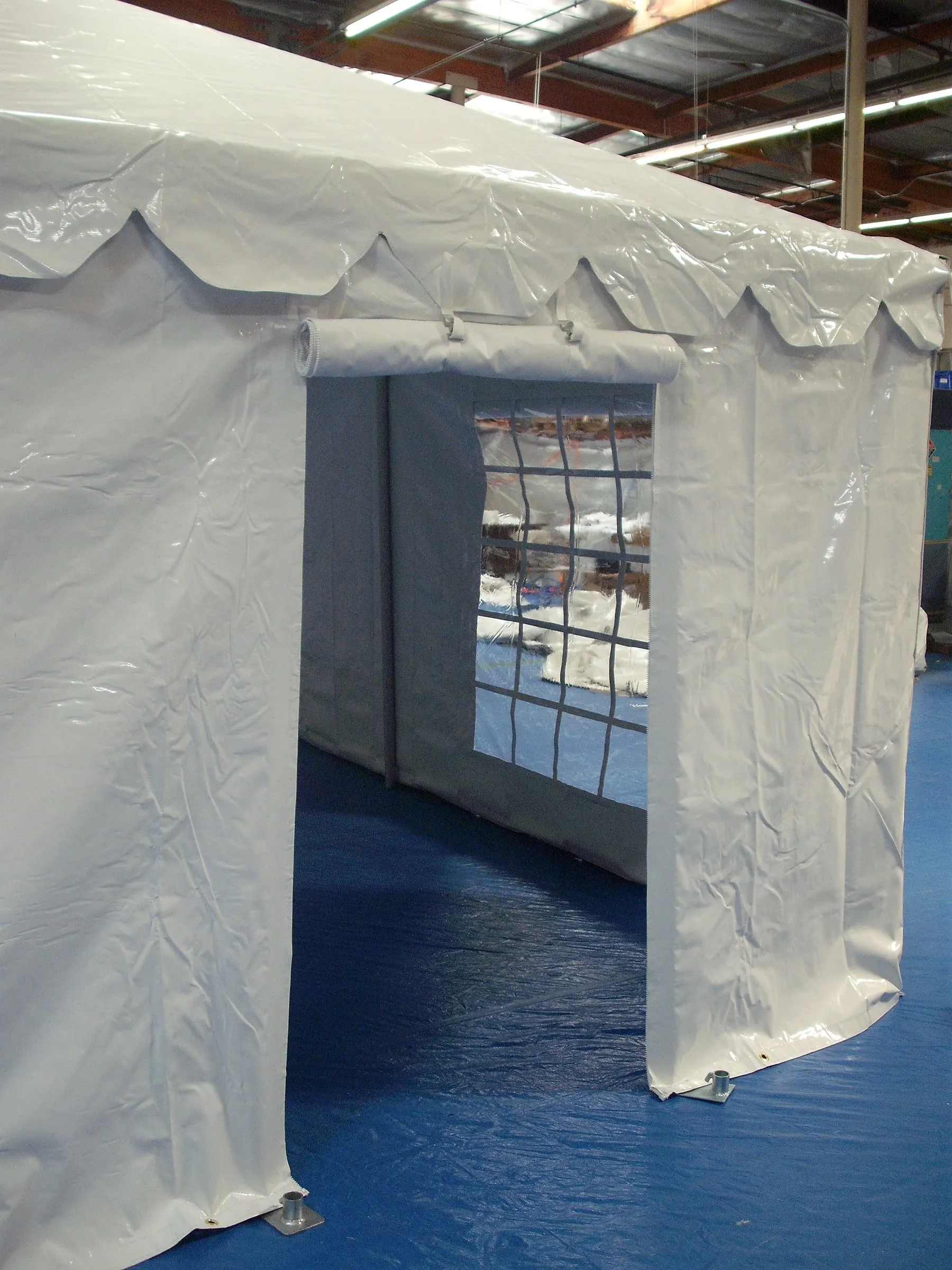 A roll-up door with a clear window in a white tent sidewall.